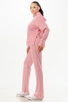 Woman wearing comfortable pink hoodie and pants set by VacationGrabs with white sneakers