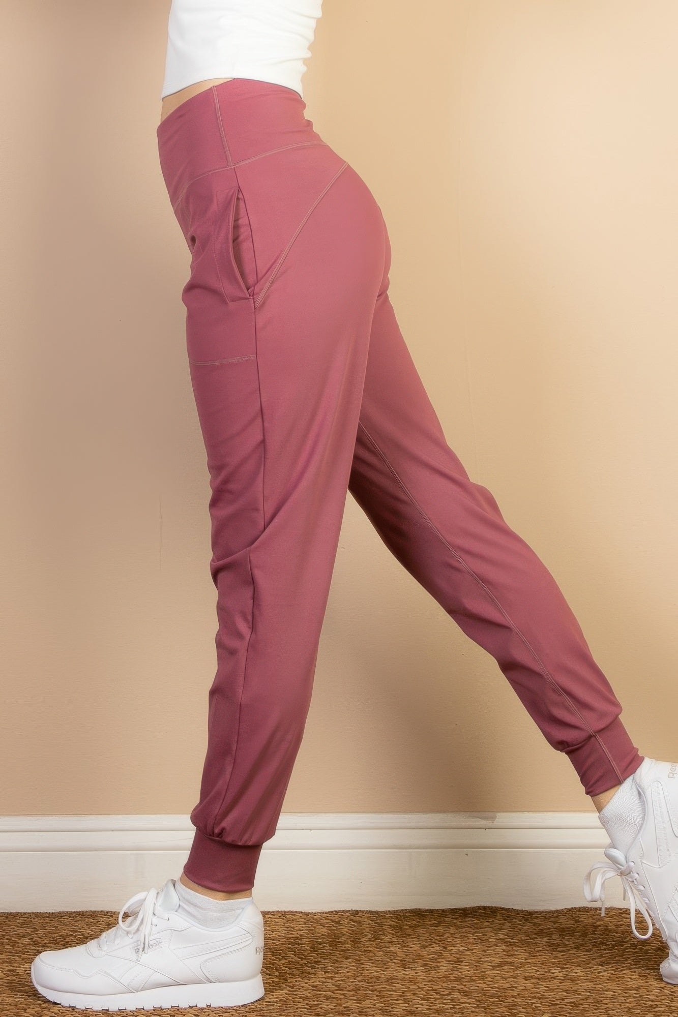 Women wearing VacationGrabs comfortable travel joggers in rose color paired with white sneakers