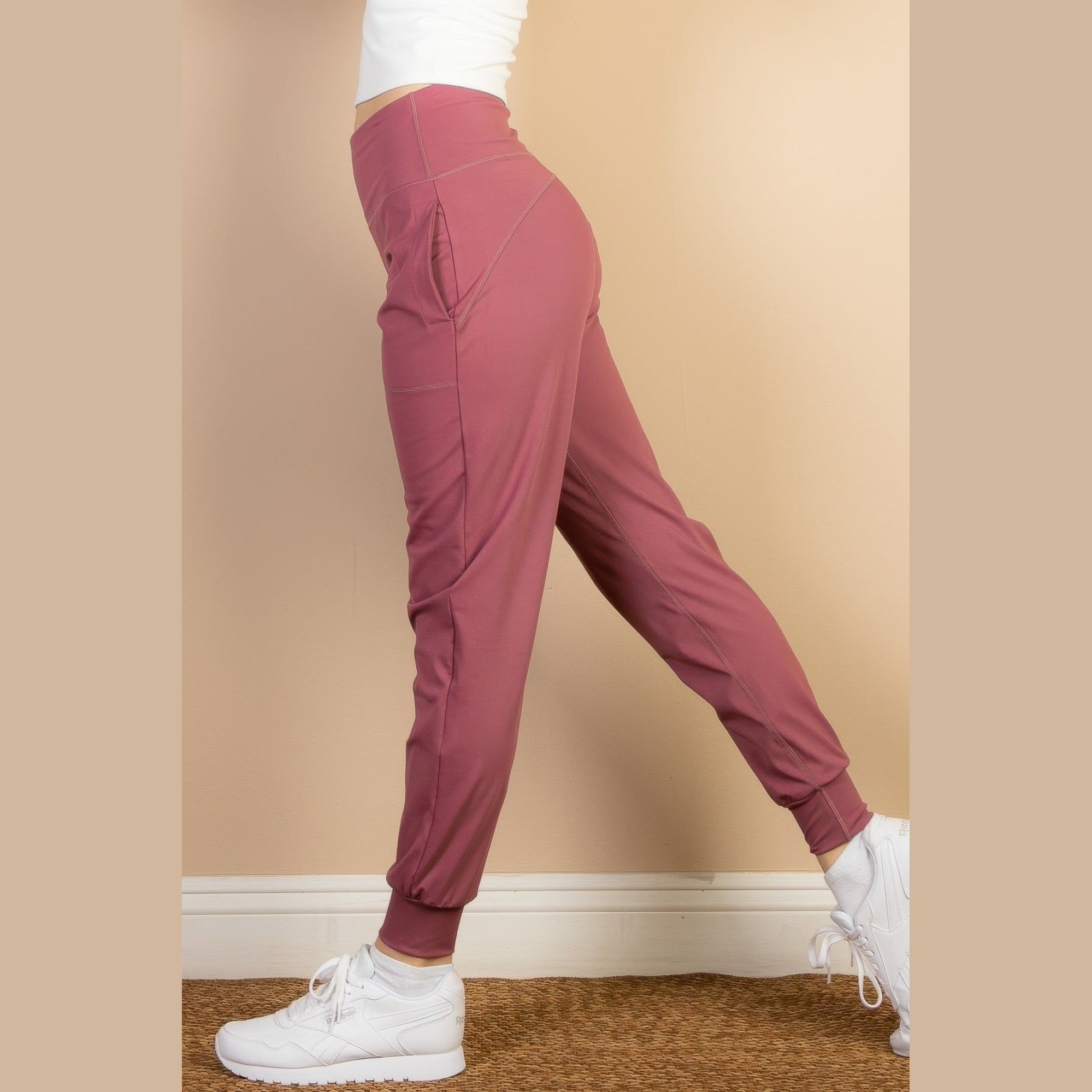 Women wearing VacationGrabs comfortable travel joggers in rose color paired with white sneakers