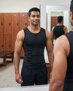 Man wearing black double-belt compression waist trainer checking fit in gym locker room mirror