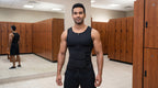Man wearing black compression waist trainer standing confidently in gym locker room, cinematic landscape view