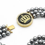 VacationGrabs crown pendant statement jewelry with black and gold design on a pearl necklace