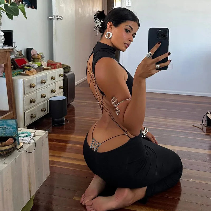 Woman wearing a black backless cut out club dress taking a mirror selfie indoors