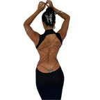Back view of a woman wearing a black backless cut out club dress with crisscross straps and butterfly detail