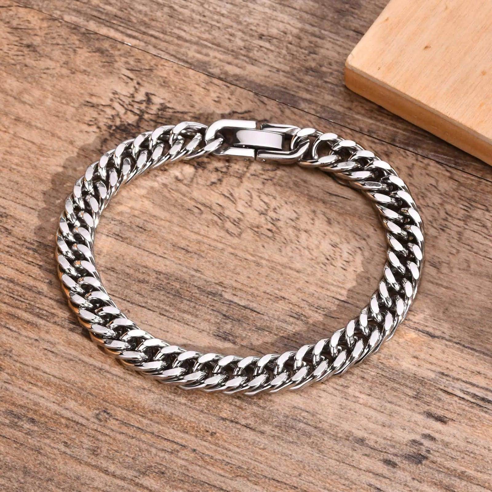 Stylish Cuban link bracelets for men in silver with a polished finish on a wooden background