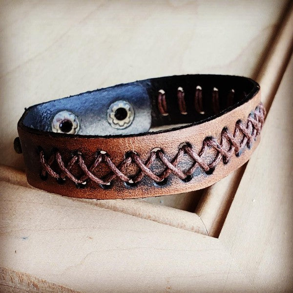 Dark brown vintage leather cuff with detailed stitching and snap closure for a stylish accessory