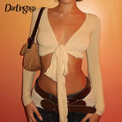 Beige womens cropped tie front top with long sleeves and deep V neckline styled with brown belt and handbag