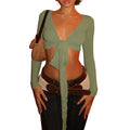 Womens cropped tie front top in sage green with long sleeves styled with dark jeans and layered belts