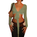 Womens cropped tie front top in sage green with long sleeves styled with dark jeans and layered belts