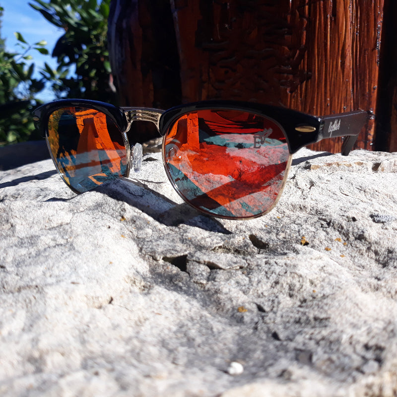 Sunglasses with reflective lenses on a rock surface with a natural background