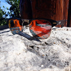 Sunglasses with reflective lenses on a rock surface with a natural background