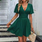Deep V waist pleated dress in green with short sleeves and a flattering fit for stylish outings