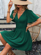 Model wearing a green deep v waist pleated dress with short sleeves, perfect for casual occasions
