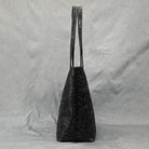 Elegant black designer shoulder bag for laptops with floral embossed pattern and long straps