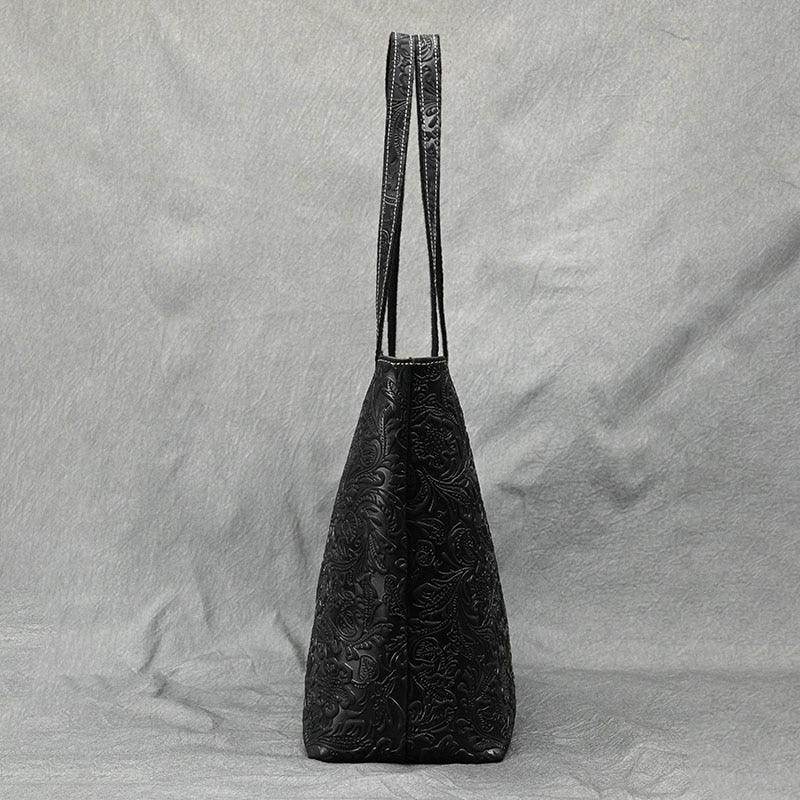 Elegant black designer shoulder bag for laptops with floral embossed pattern and long straps