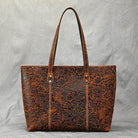 Stylish brown designer shoulder bag for laptops with intricate floral detailing and sturdy handles