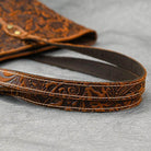 Close-up of a stylish designer shoulder bag for laptops with intricate patterns and sturdy straps.