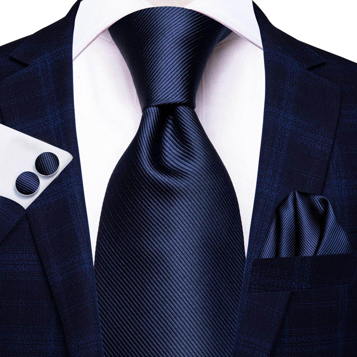 Stylish designer wedding ties for men in a classic navy color, paired with a sharp suit and pocket square.