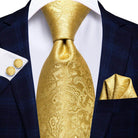 Elegant gold designer wedding ties for men featuring a paisley pattern, styled with a navy suit