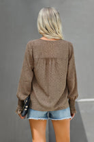 Back view of a women's dot v neck ruffle blouse in brown paired with denim shorts