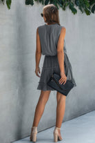 Back view of a stylish grey drawstring summer dress for women, paired with a black clutch and high heels