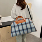 Blue plaid duffle bag with brown leather handles for travel
