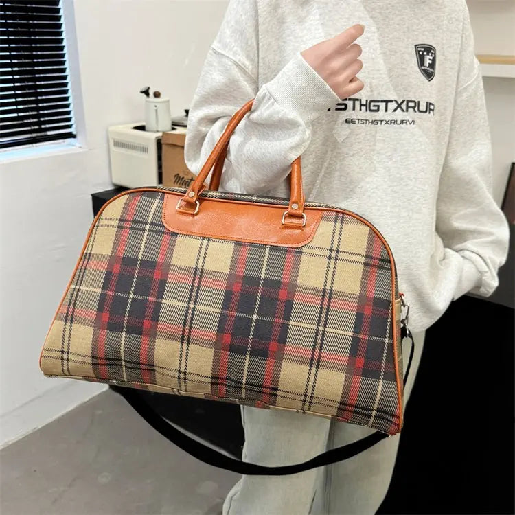 Plaid duffle bag with brown leather handles for travel