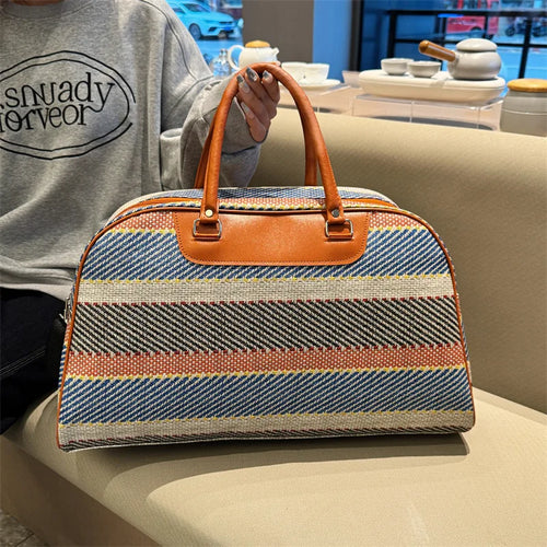 Striped duffle bag with brown leather handles for travel