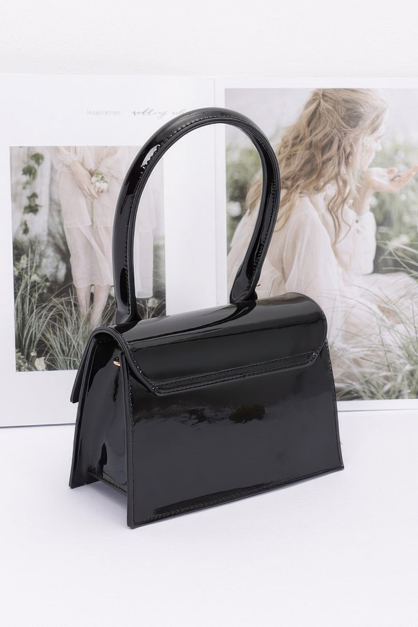 Sleek black enamel top handle crossbody bag with stylish glossy finish and elegant design