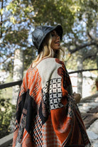 Stylish woman wearing an ethical fashion bucket hat with a patterned poncho in a natural setting