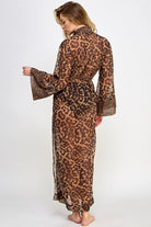 Model wearing a long sheer leopard print womens robe with belt and flared sleeves back view