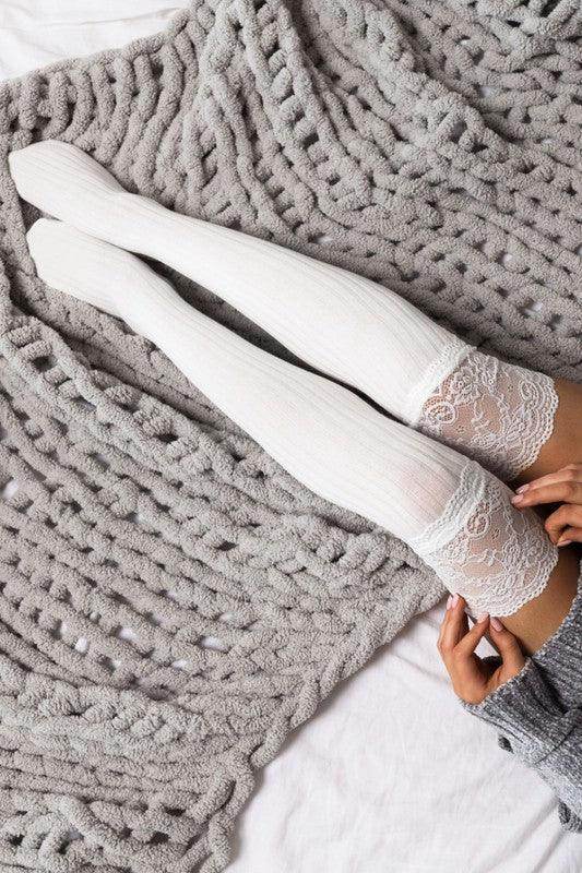 Aili's Corner fashionable knee high socks in white with lace trim, styled on a cozy grey blanket