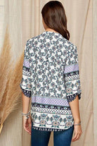 Back view of a women's floral roll up sleeve top with intricate patterns in soft colors