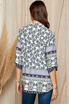 Back view of a women's floral roll up sleeve top with intricate patterns in soft colors