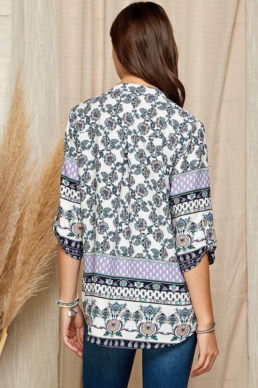 Back view of a women's floral roll up sleeve top with intricate patterns in soft colors