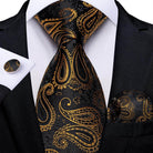 Elegant formal neck tie for men in black and gold paisley design, matching pocket square and cufflinks