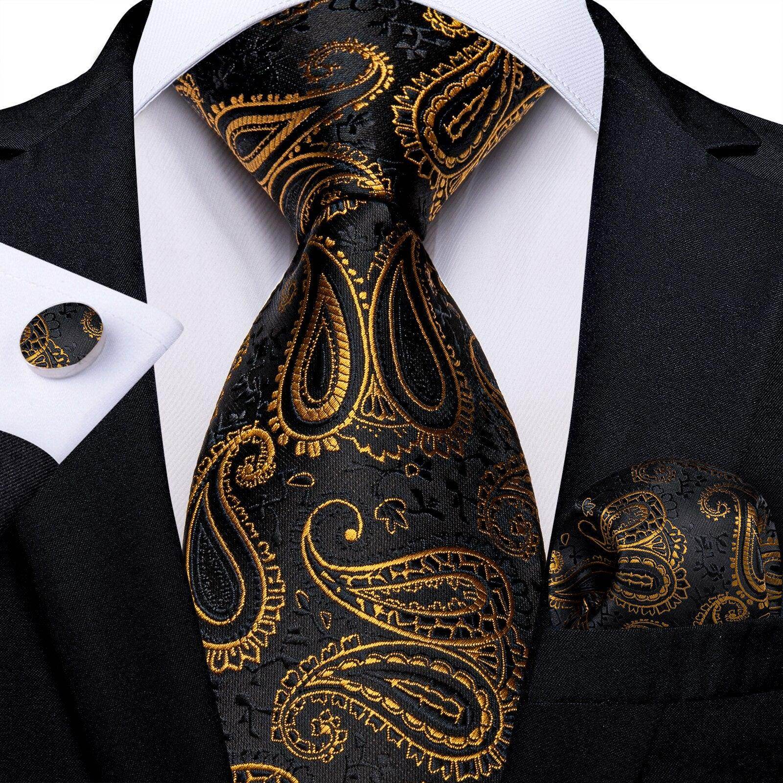 Elegant formal neck tie for men in black and gold paisley design, matching pocket square and cufflinks
