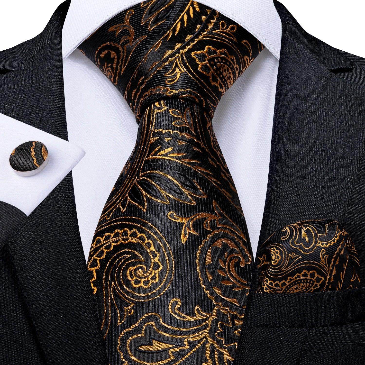 Elegant formal neck tie for men with a paisley design in black and gold, paired with matching cufflinks