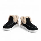 Black slip-on shoes with fur trim worn with blue jeans on a white background