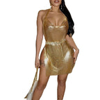 Woman wearing a gold glitter backless mini dress with halter neck and side slit holding a white purse