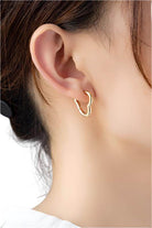 Gold heart shape huggie hoop earrings displayed on a model's ear for a stylish look