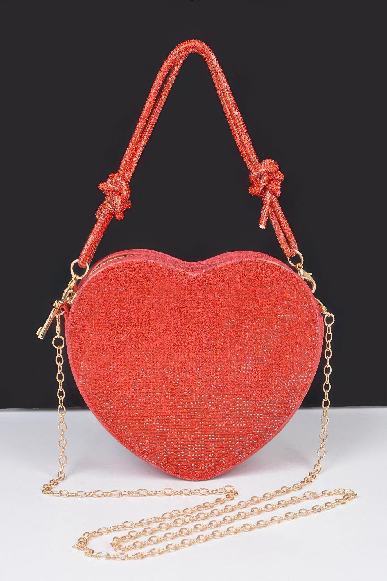 Heart shaped evening purse in red with a sparkling finish and a gold chain strap for stylish outings