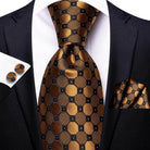 Stylish gold paisley formal tie paired with a matching pocket square and cufflinks for a sophisticated look
