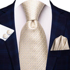 Gold paisley formal tie on a dark navy suit with a matching pocket square and cufflinks