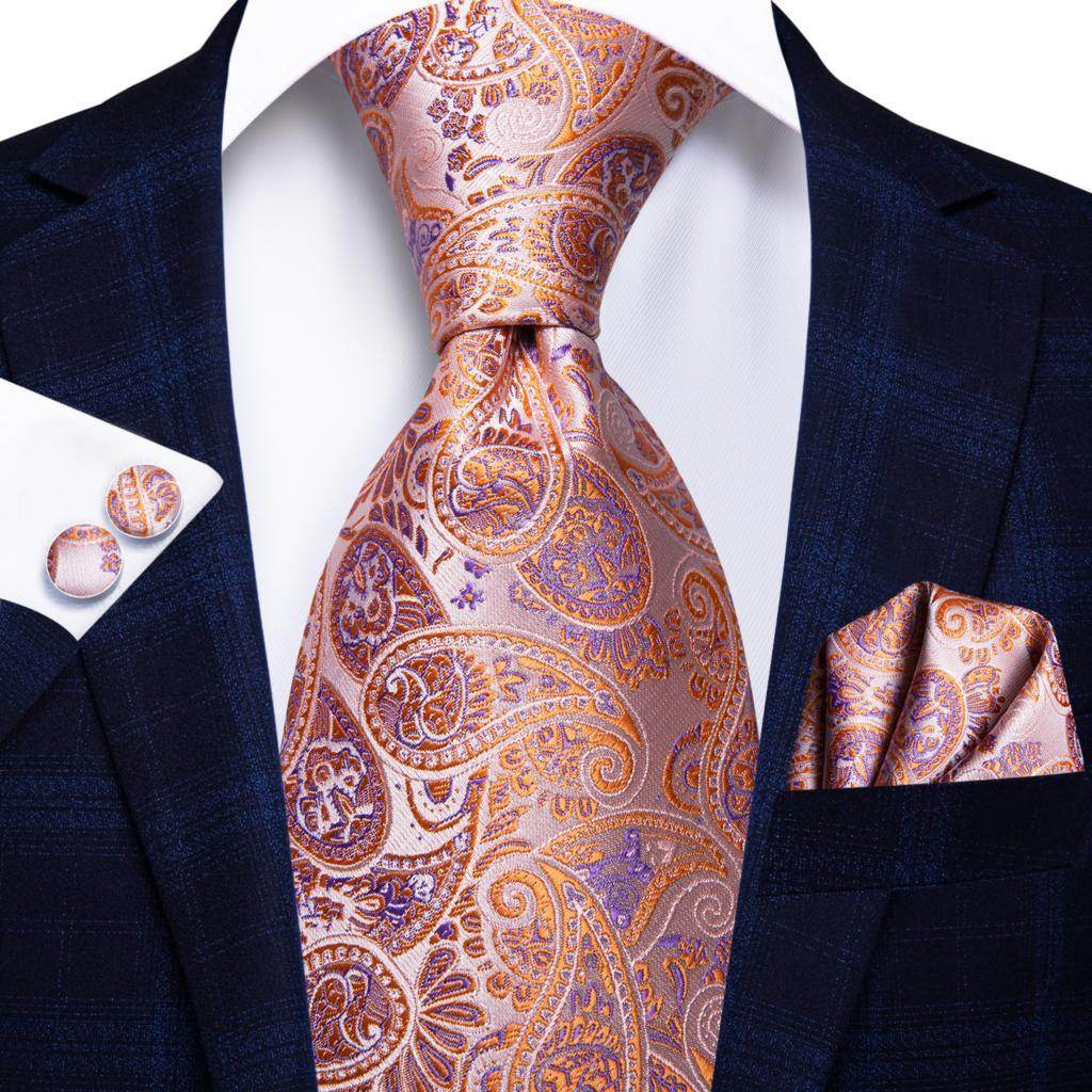 Gold paisley formal tie alongside matching pocket square and cufflinks in elegant suit attire