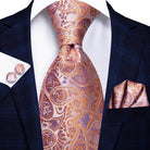 Gold paisley formal tie alongside matching pocket square and cufflinks in elegant suit attire