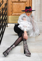 Stylish high heel statement boots for women with sequins, paired with a chic black outfit and hat