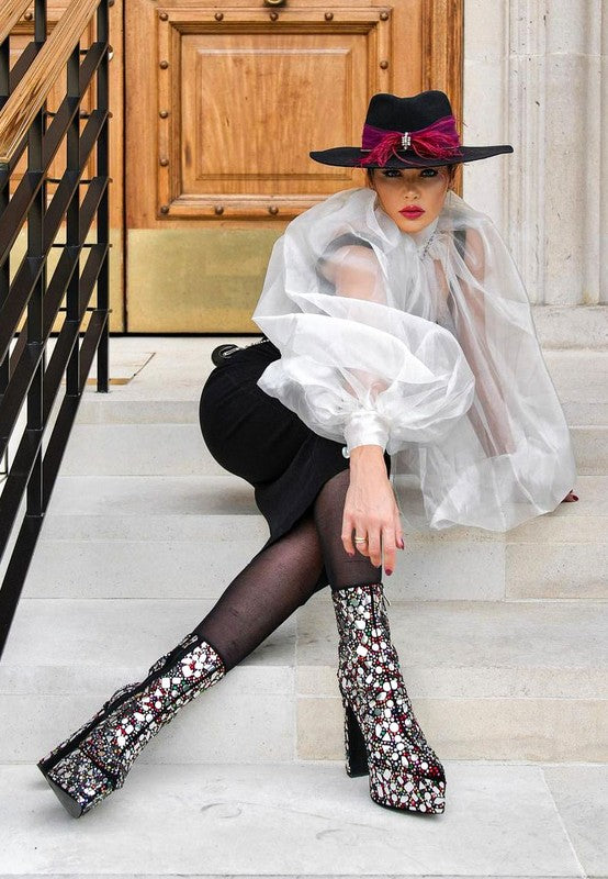 Stylish high heel statement boots for women with sequins, paired with a chic black outfit and hat