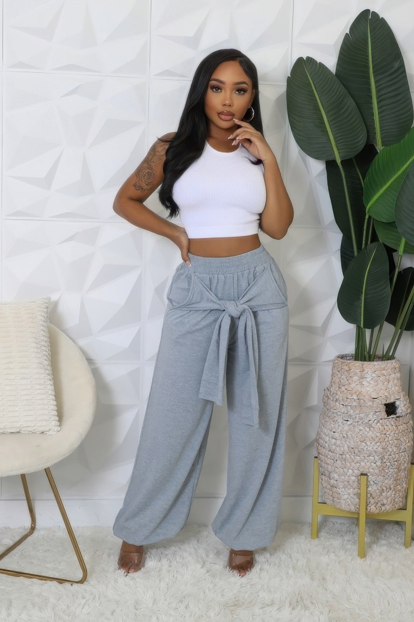 Woman wearing gray high waisted stretch pants with front tie detail and white crop top
