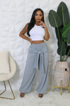 Woman wearing gray high waisted stretch pants with front tie detail and white crop top